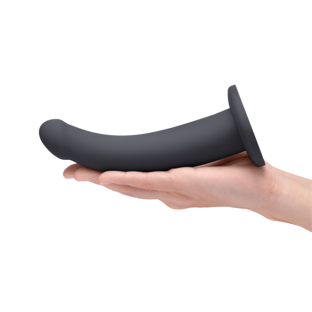 b-Vibe Essentials 7 Inch Smooth Silicone Dildo Black held in a hand for scale and demonstration.