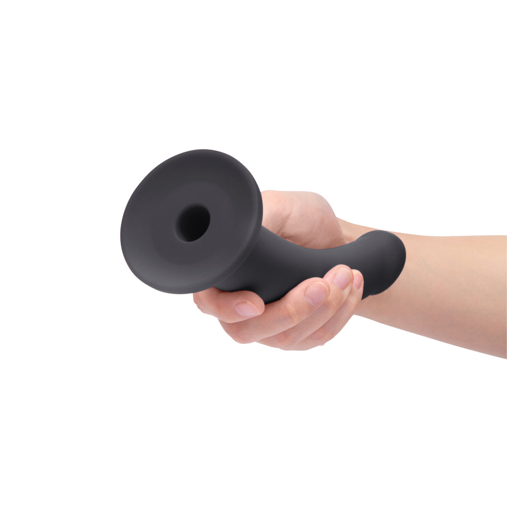 b-Vibe Essentials 7 Inch Smooth Silicone Dildo Black held in a hand, showcasing its sleek and minimalist design.