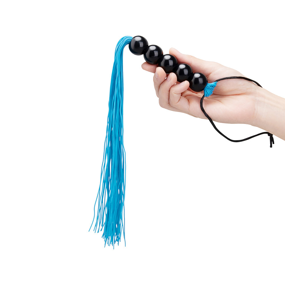 B-vibe Essentials Beaded Flogger showcasing a hand holding the colorful flogger with black beads and blue tassels.