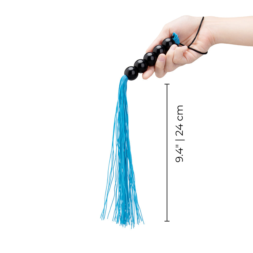 B-vibe Essentials Beaded Flogger held in hand, featuring a blue tassel and black beads, measuring 9.4 inches.