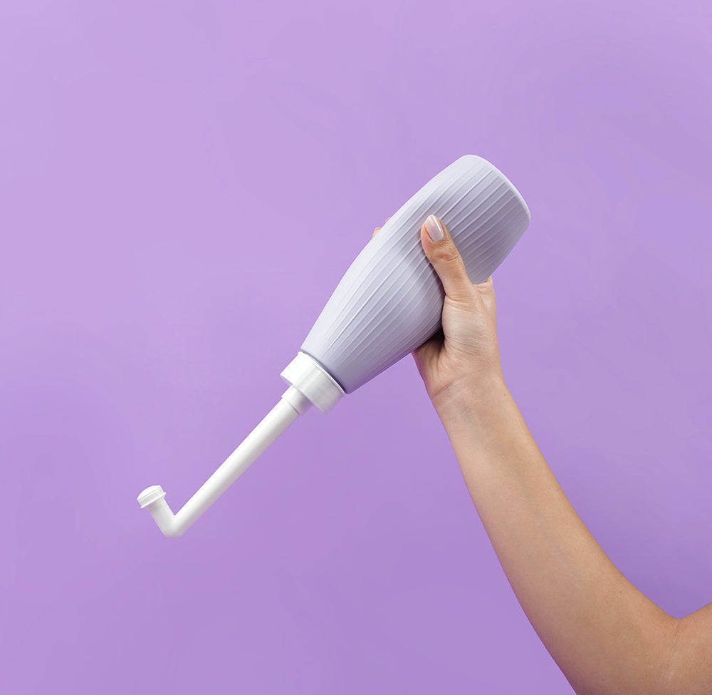 Uva Vaginal & Perineal Wash Bottle held in hand against a purple background, designed for gentle intimate cleansing.