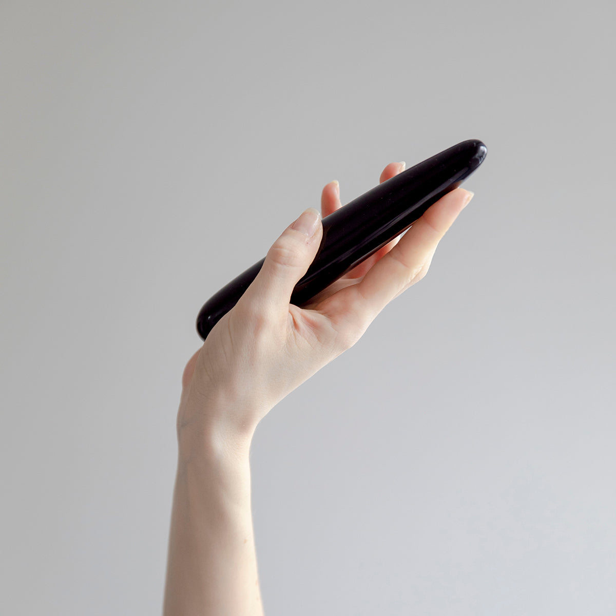 Chakrubs Xaga Slim Non-Phallic Dildo held in hand against a neutral background for elegant internal pleasure.