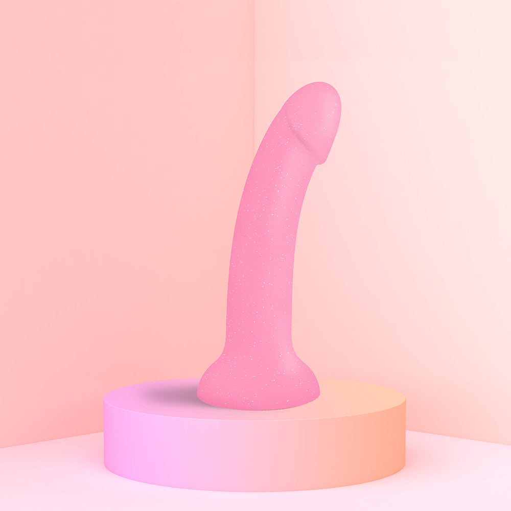 Dildolls Glitzy 7 inch Silicone Dildo Pink Glitter on a display pedestal against a soft pink background.