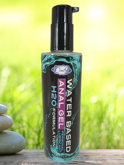 Cloud 9 H2o Anal Play Gel 8 Oz bottle displayed outdoors on smooth stones with green grass background.
