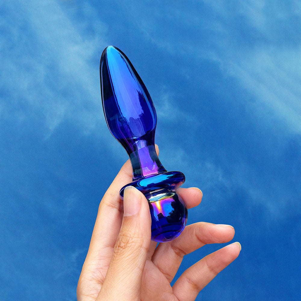 Biird Anii Glass Anal Plug in hand, showcasing its elegant design and vibrant blue color against a blue background.