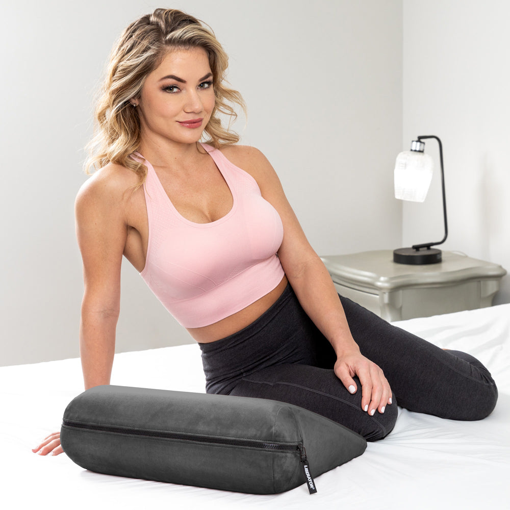 Liberator Jaz Original Sex Positioning Pillow Black displayed on a bed with a model, highlighting its design and use.