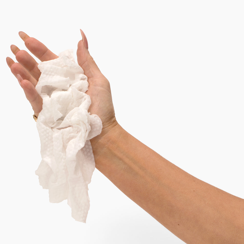 Hand holding crumpled tissues from the Beloved Freshen Up Travel Kit, perfect for on-the-go hygiene.