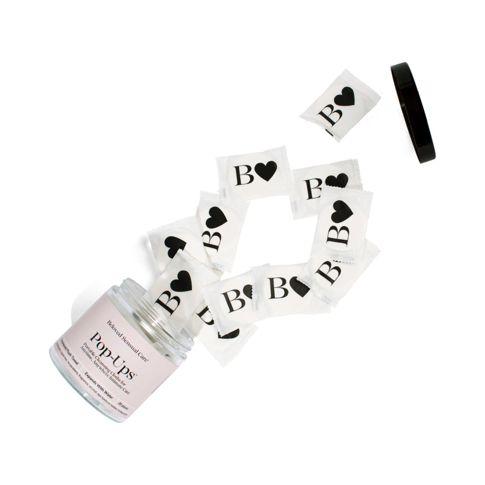 Beloved Pop-Up Cleansing Cloths in a jar with individual packs scattered around, showcasing a travel-friendly hygiene solution.