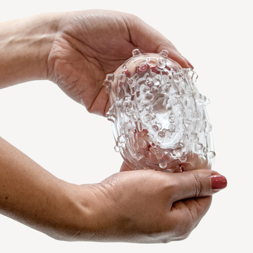 The Handy TrueGrip Gen 2 Masturbator Sleeve Clear held in hands with textured exterior.