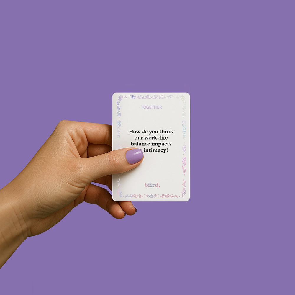 A hand holding a card from the Biird X Jouissance Club Together Couples Card Game with a question about intimacy.