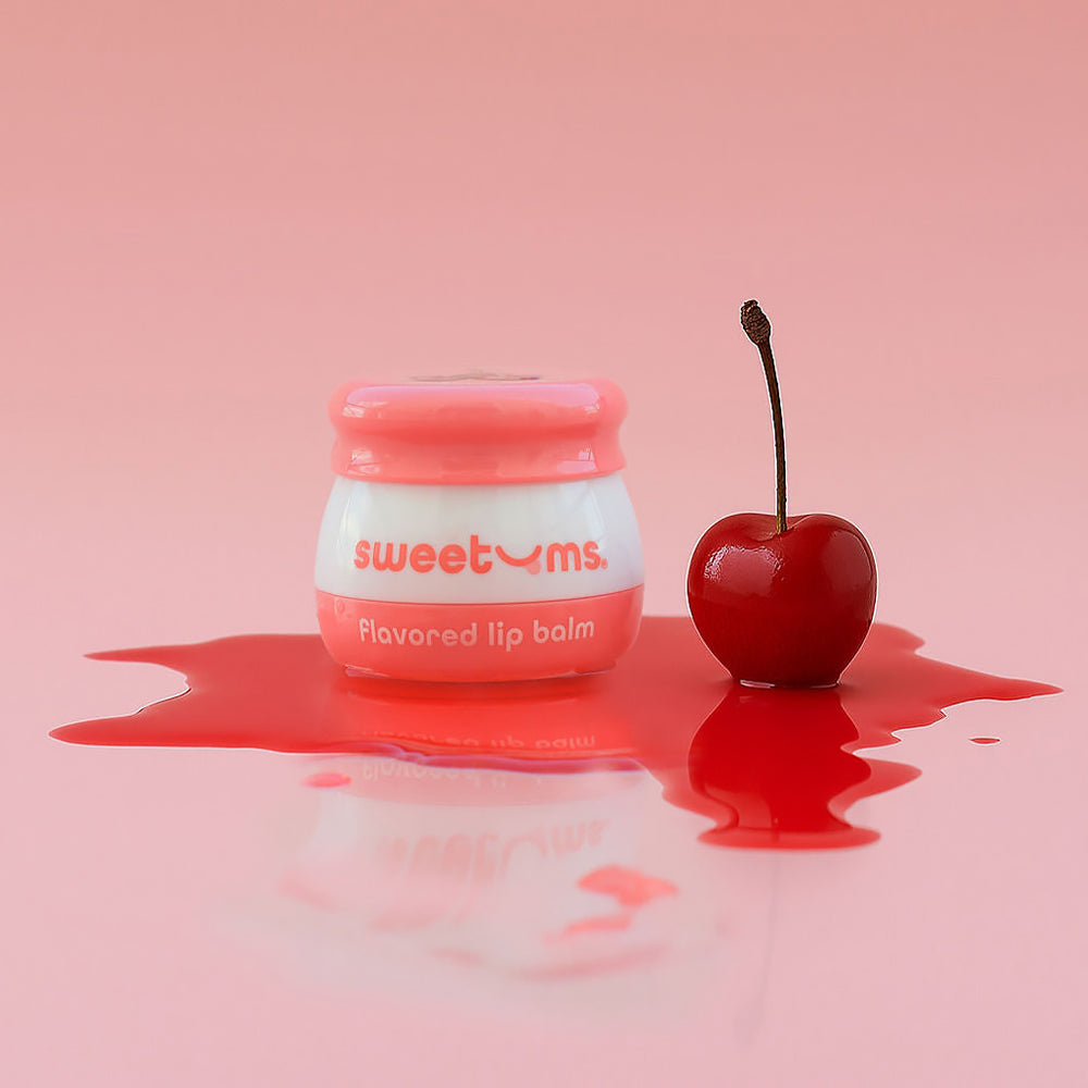Sweetums Cherry Flavored Lip Balm with a cherry, showcasing juicy flavor and hydration on a pink background.