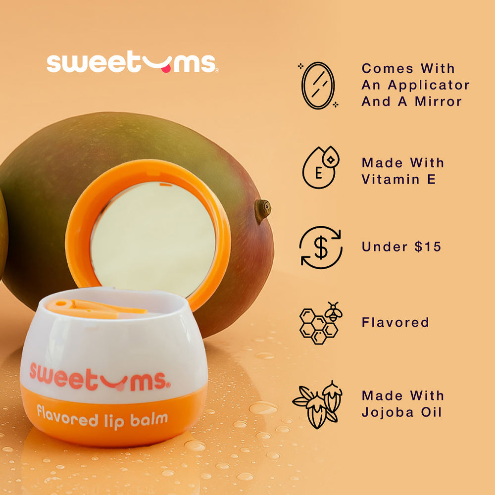 Sweetums Mango Flavored Lip Balm with mirror and applicator next to fresh mangoes, highlighting vitamin E and jojoba oil.