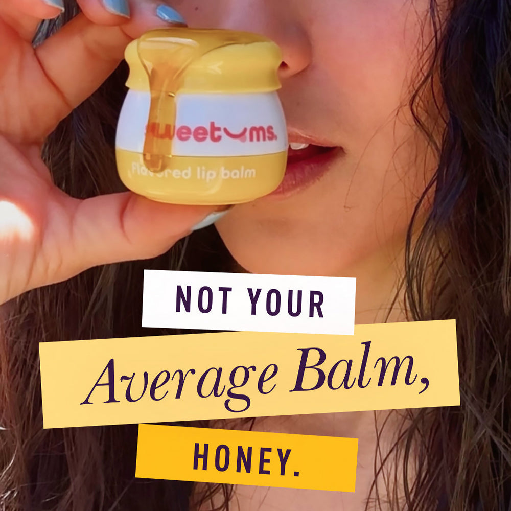 Sweetums Honey Flavored Lip Balm in a person's hand, showcasing its glossy finish and honey flavor.