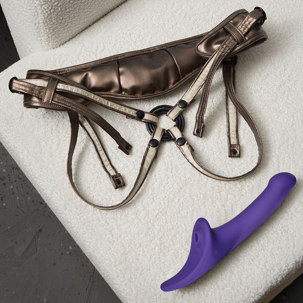 Strap-on-me Multi Orgasm Dildo Medium Purple alongside its harness on a soft, textured surface.