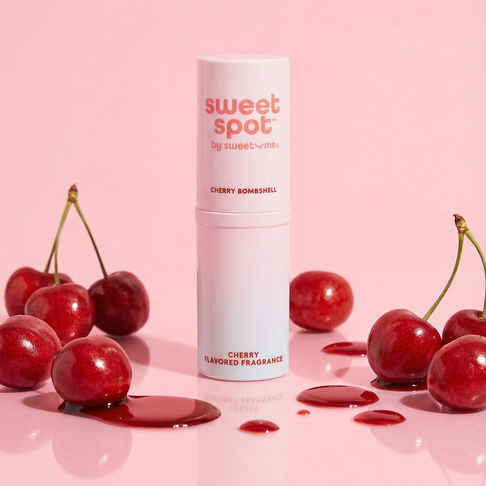Sweetums Sweet Spot Flavored Fragrance Cherry Bombshell perfume stick with cherries on a pink background.