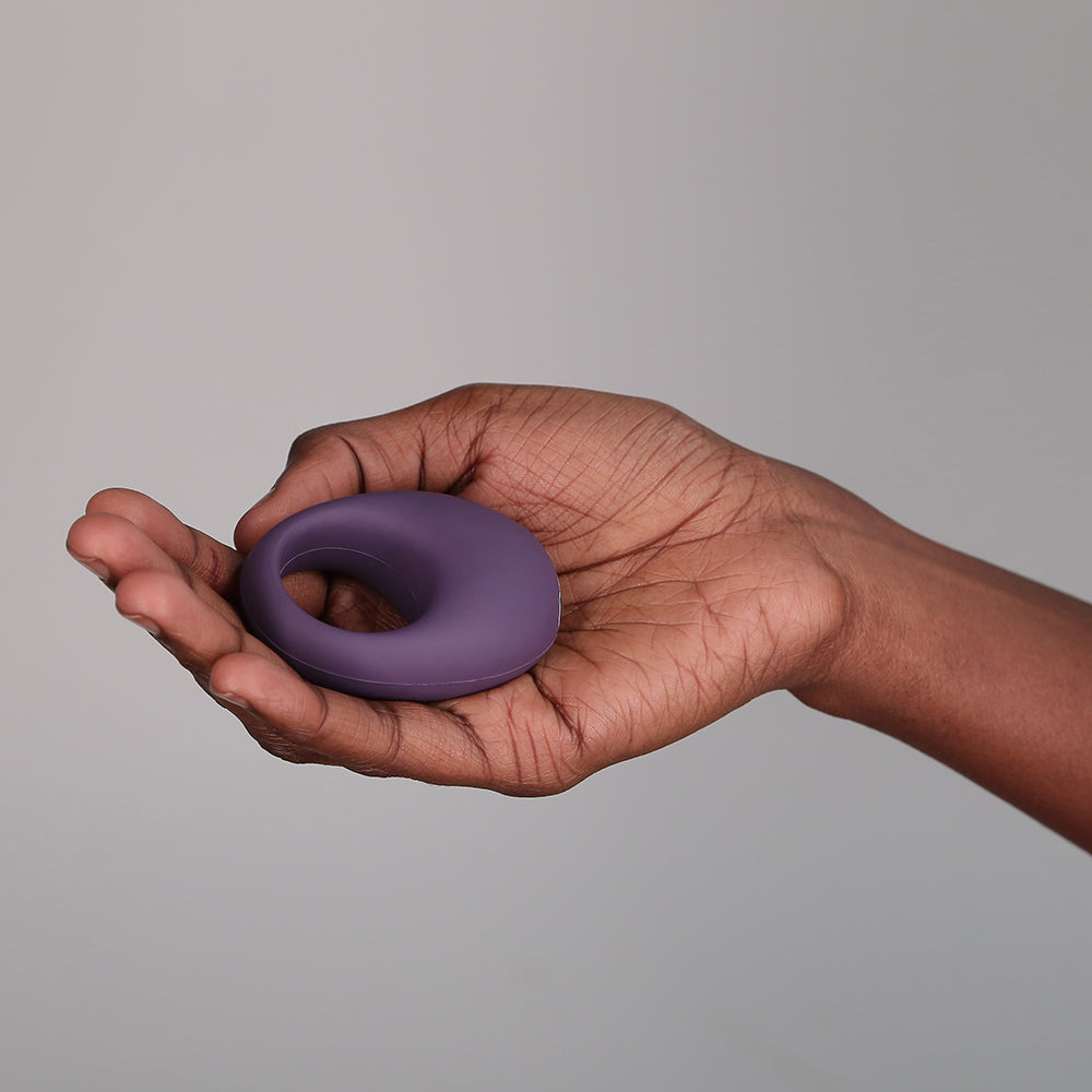Je Joue Mio V2 Vibrating Cock Ring Purple held in a hand against a neutral background.