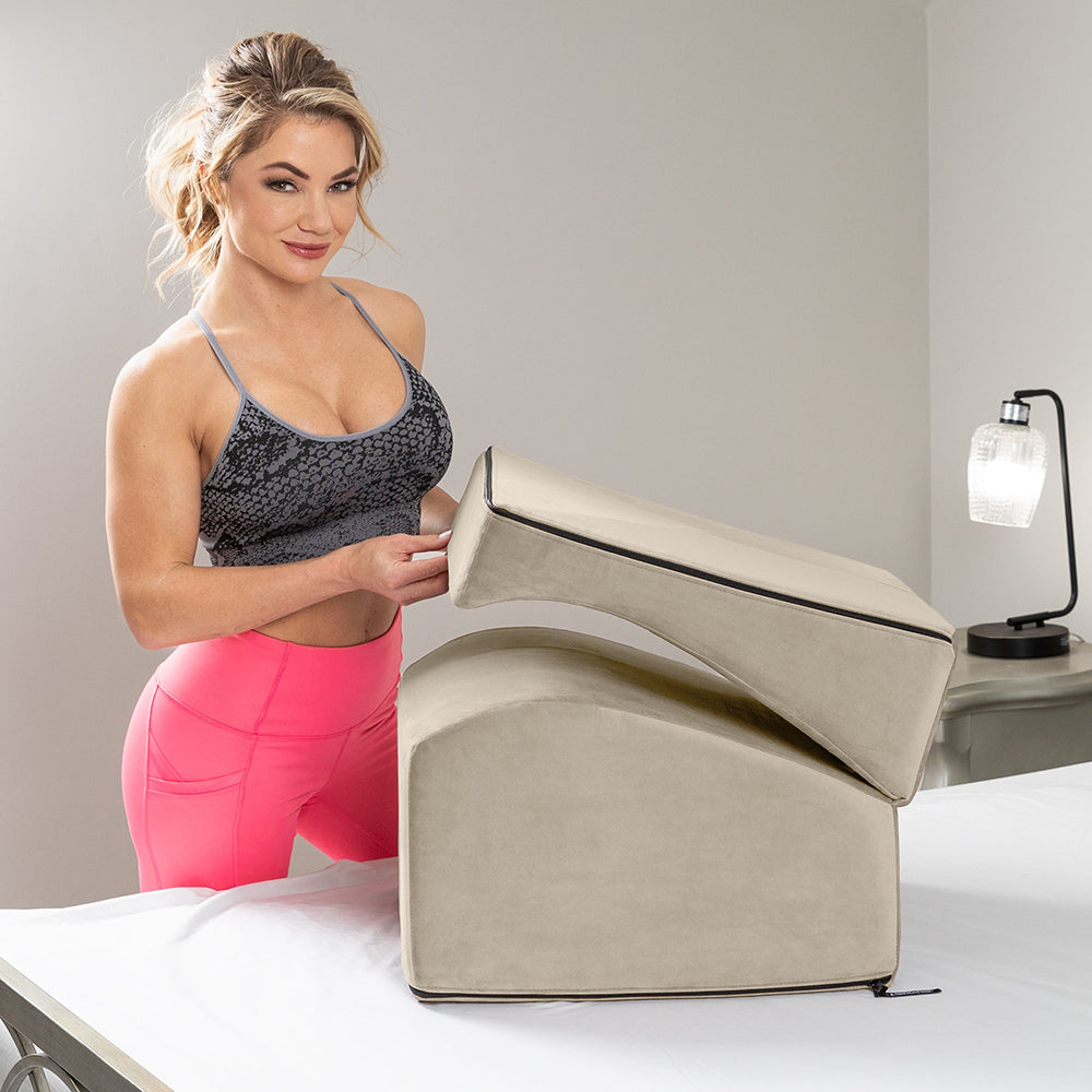 Woman demonstrating Liberator Flip Ramp Sex Positioning Pillow With Slip Cover Cream on a bed.
