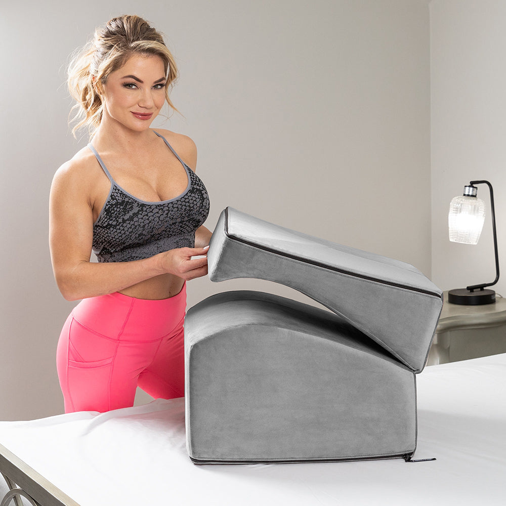 Liberator Flip Ramp Sex Positioning Pillow With Slip Cover Grey displayed on a bed with a model demonstrating its use.