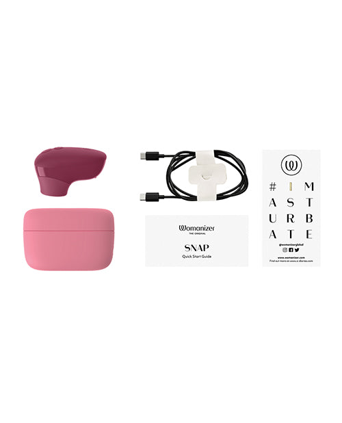 Womanizer Snap Clitoral Stimulator Crushed Berry with charging cable and quick start guide.