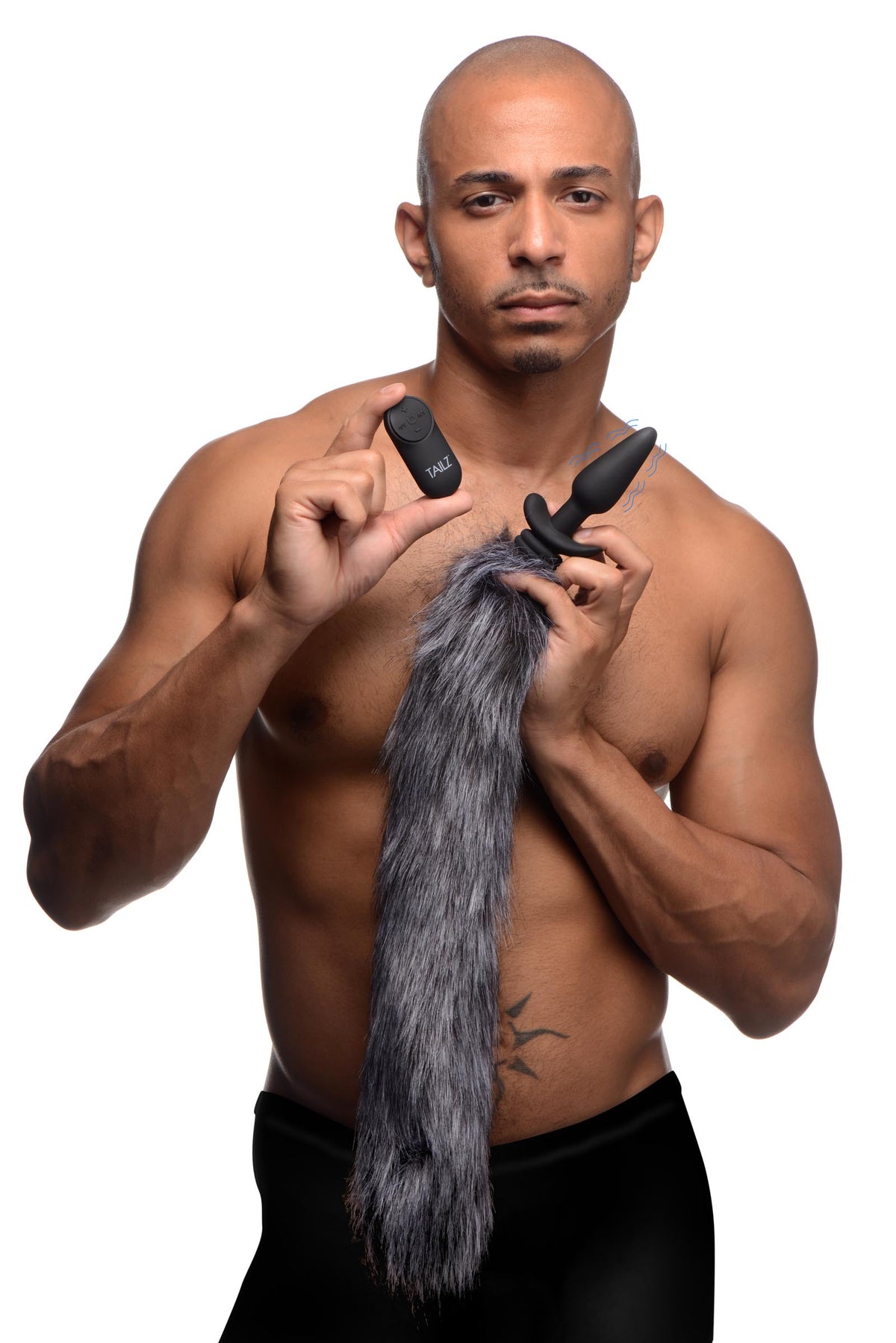 Vibrating Silicone Anal Plug with 3 Interchangeable Tails held by a man with a remote and gray fox tail.