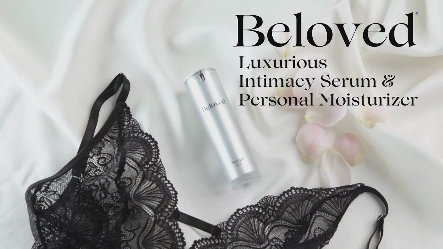 Beloved Intimacy Serum 15 ml next to black lace lingerie and rose petals on a soft white fabric surface.