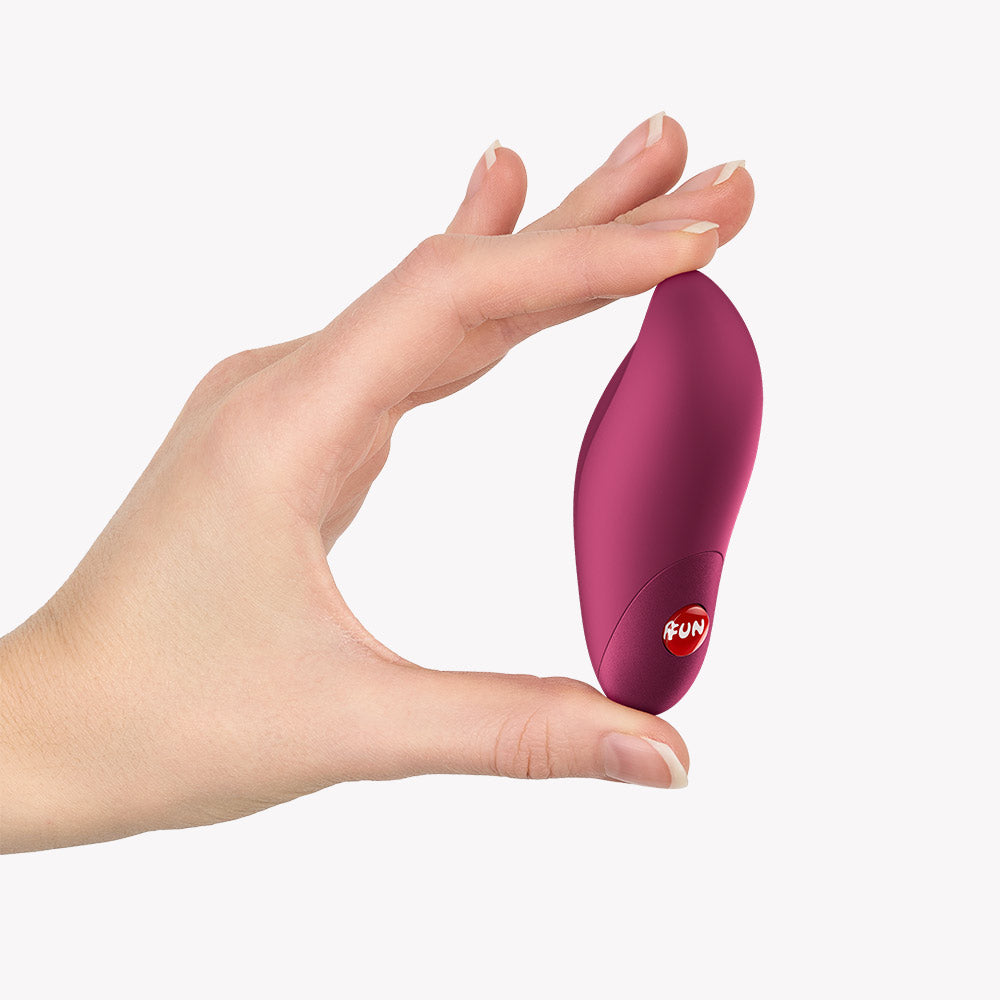 Fun Factory Charme Bullet Vibrator Wine Red held in a hand, showcasing its compact size and design.