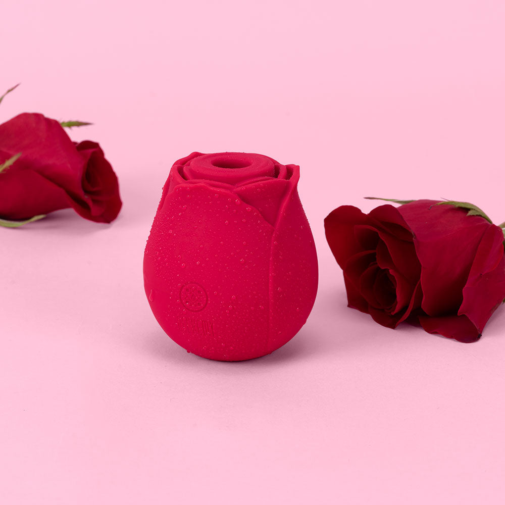 Alchemy Rosebud Luxury Air-Pulse Massager Red in a pink setting surrounded by red rose petals.