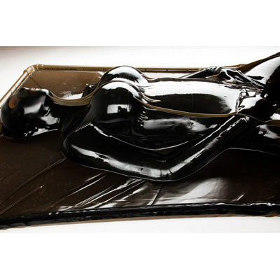 Extreme Black Latex Vacuum Bed with a figure sealed in black latex for complete immobilization.